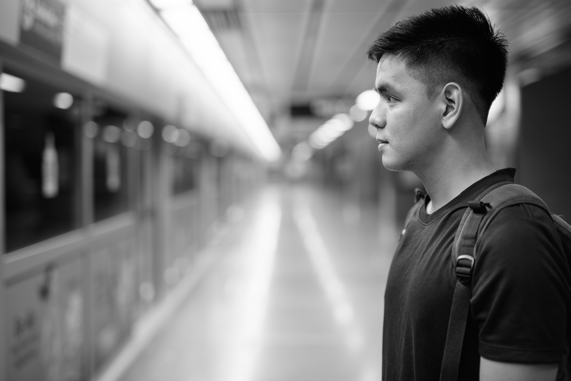 Young handsome Asian tourist man waiting for the train at the subway station